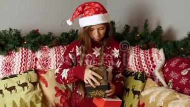 圣诞帽中悲伤而不快乐的女孩在新年装饰中<strong>打开</strong>圣诞<strong>礼盒</strong>